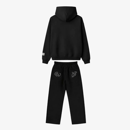Black oversized tracksuit back view. Premium heavyweight cotton fleece two-piece set featuring a hoodie and matching sweatpants with white outline embroidery on the back pockets.