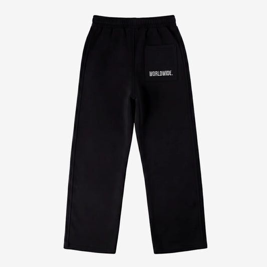 Back view of the CELESTIC Black Basic sweatpants laid flat on a white background. These premium black cotton fleece pants feature a relaxed straight-leg silhouette and a back pocket with prominent white script logo embroidery.
