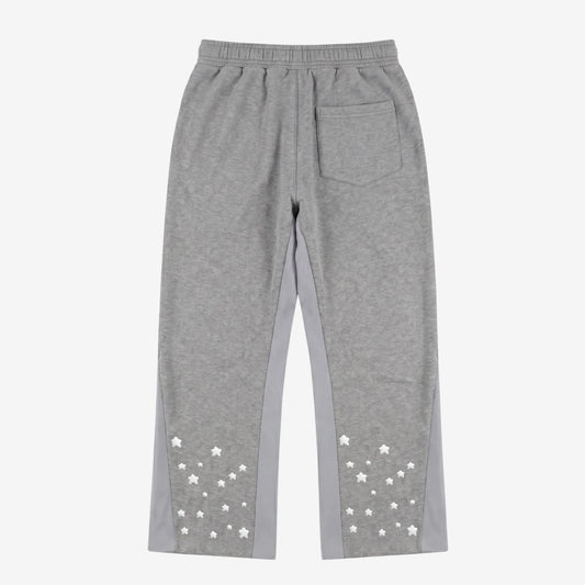 Back view flat-lay photograph of the CELESTIC Grey Star Pants on a white background. These premium heather grey cotton fleece sweatpants feature light grey side panels, a relaxed fit, and a single back pocket on the right side. The lower back of both legs is detailed with multiple scattered white embroidered stars, highlighting the unique streetwear aesthetic of the Star collection.