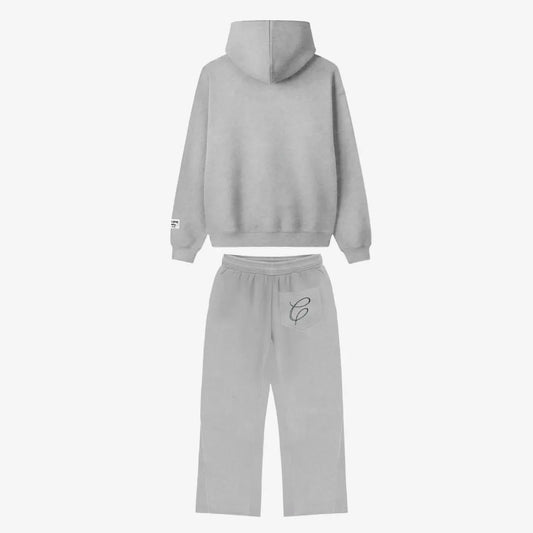 Back view flat-lay photograph of the CELESTIC Grey Zipper Tracksuit on a white background. The set includes a premium heather grey zip-up hoodie with a structured hood and a woven brand patch on the left sleeve cuff. The matching relaxed-fit sweatpants feature a single back pocket on the right side, detailed with an elegant black embroidered 'C' script logo.