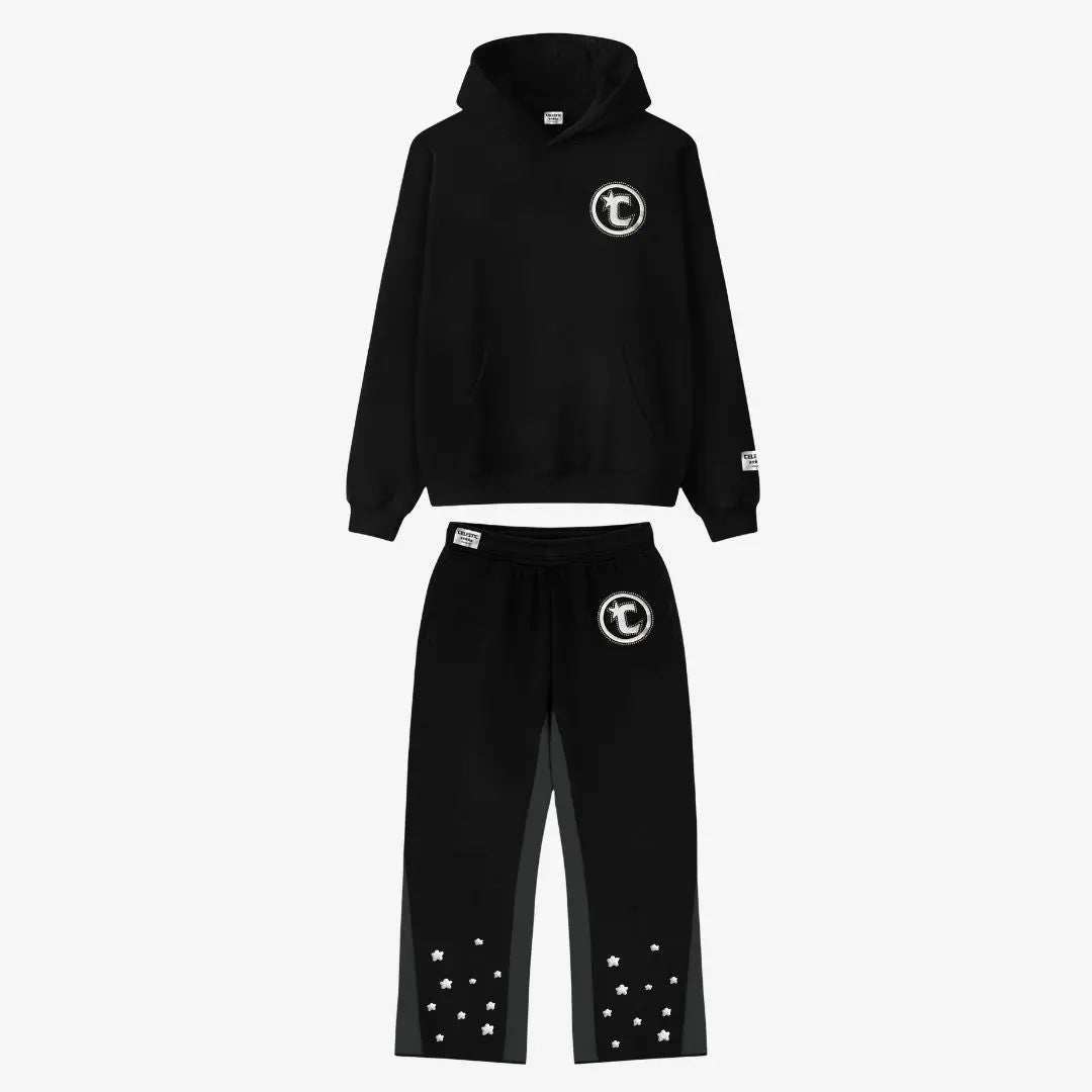 Main product image of the CELESTIC Black Star Tracksuit set. This premium heavyweight black cotton fleece ensemble features an oversized hoodie with a white circular 'C' star logo on the chest and matching relaxed sweatpants with the same logo on the thigh and multiple white embroidered stars at the leg openings. 