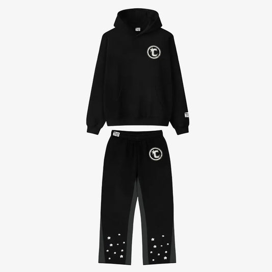 Main product image of the CELESTIC Black Star Tracksuit set. This premium heavyweight black cotton fleece ensemble features an oversized hoodie with a white circular 'C' star logo on the chest and matching relaxed sweatpants with the same logo on the thigh and multiple white embroidered stars at the leg openings. 