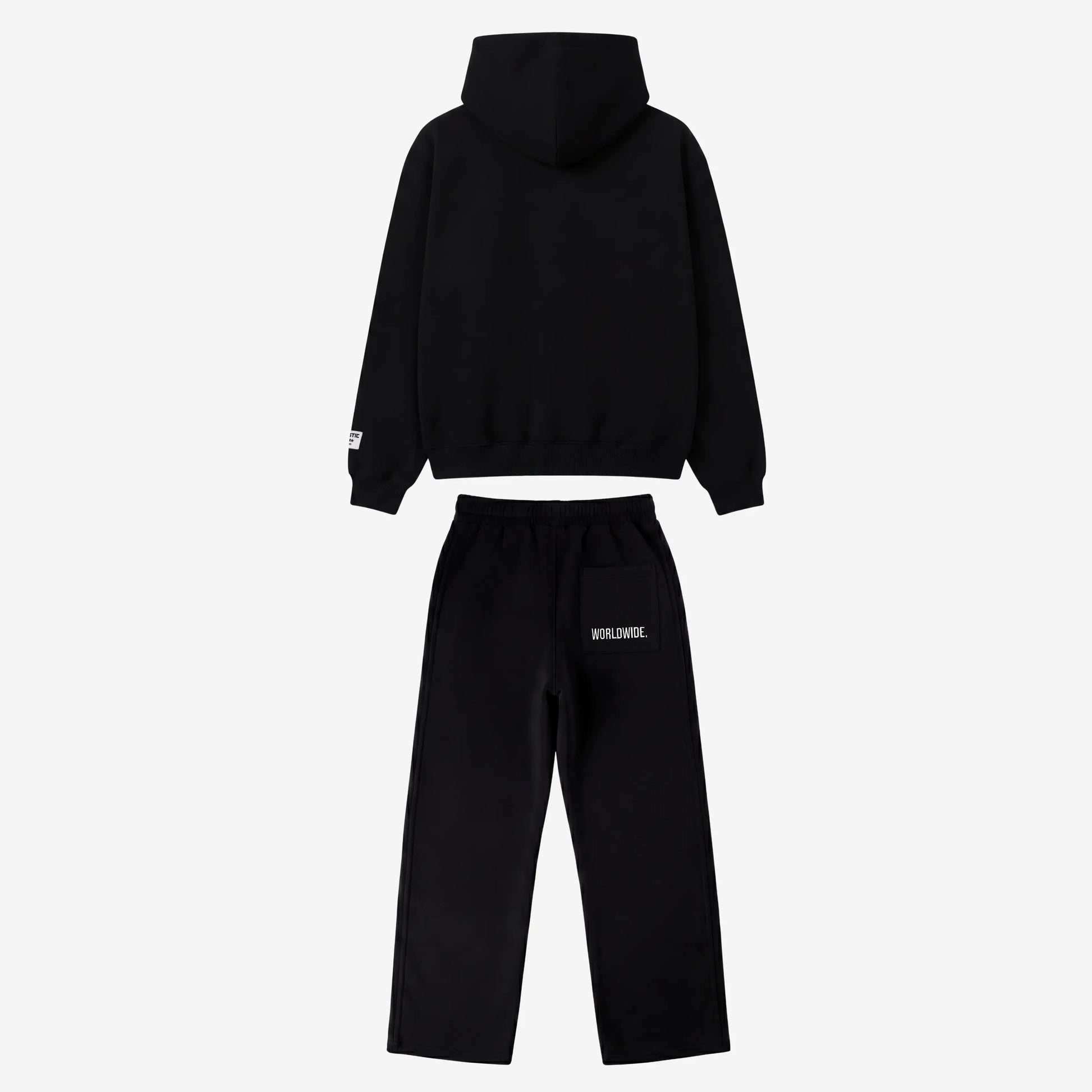 Back view of the full CELESTIC Black Basic Tracksuit set laid flat on a white background. This premium heavyweight black cotton fleece ensemble features an oversized zip-up hoodie with a structured hood and matching relaxed straight-leg sweatpants with white 'WORLDWIDE.' embroidery on the back pocket.