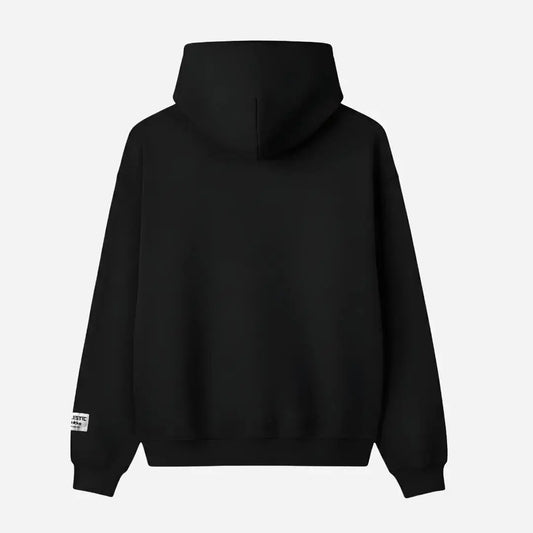 Back view flat-lay photograph of the CELESTIC Black Gemstone Hoodie on a white background. This premium heavyweight black cotton fleece pullover features a clean, minimalist back design without graphics, a structured double-lined hood, and ribbed cuffs and hem. A distinct woven CELESTIC brand patch with white text is visible on the left sleeve cuff.