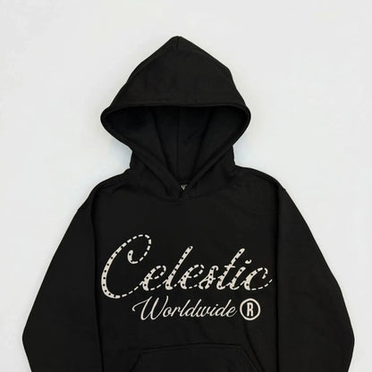A detailed close-up flat-lay photograph of the upper section of the CELESTIC Black Gemstone Hoodie on a white background. Highlighting the premium heavyweight black cotton fleece fabric and the structured double-lined hood. The chest features a large white screen-printed 'Celestic' script logo beautifully embellished with sparkling rhinestones, with the white printed text 'Worldwide ®' situated underneath.