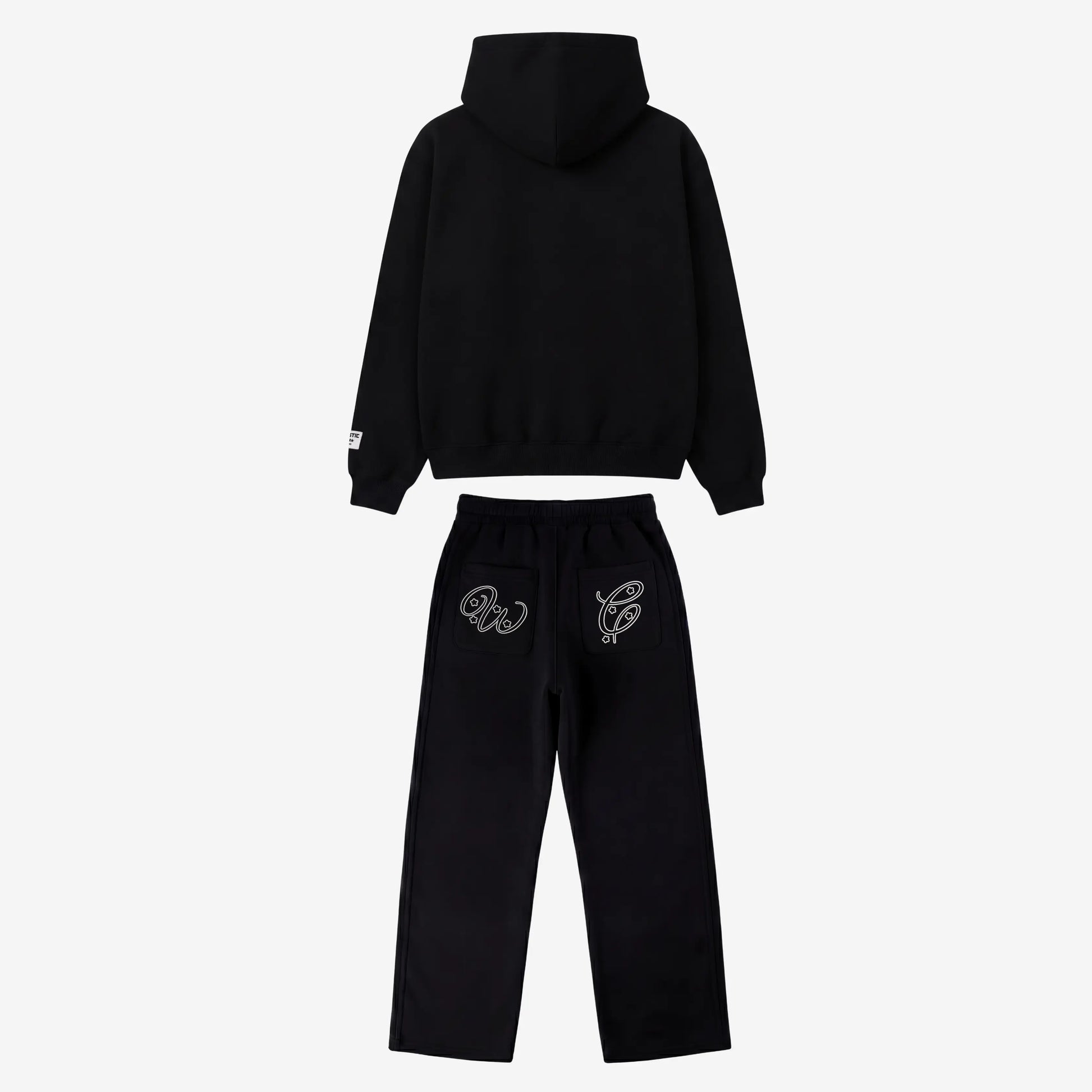 Black oversized tracksuit back view. Premium heavyweight cotton fleece two-piece set featuring a hoodie and matching sweatpants with white outline embroidery on the back pockets.