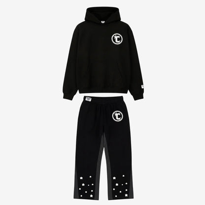 Main product image of the CELESTIC Black Star Tracksuit set. This premium heavyweight black cotton fleece ensemble features an oversized hoodie with a white circular 'C' star logo on the chest and matching relaxed sweatpants with the same logo on the thigh and multiple white embroidered stars at the leg openings. 