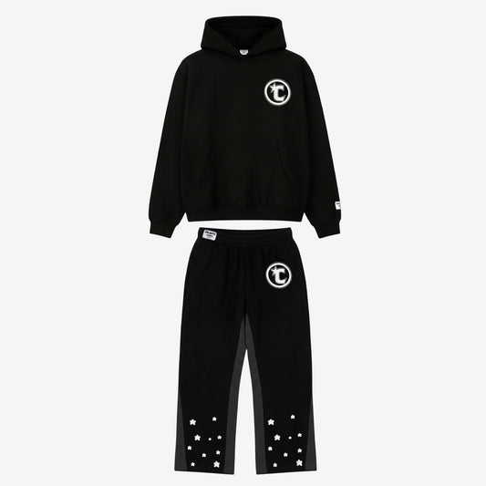 Main product image of the CELESTIC Black Star Tracksuit set. This premium heavyweight black cotton fleece ensemble features an oversized hoodie with a white circular 'C' star logo on the chest and matching relaxed sweatpants with the same logo on the thigh and multiple white embroidered stars at the leg openings. 