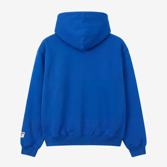 Blue oversized full-zip hoodie back view laid flat on a white background. The premium heavyweight cotton fleece CELESTIC Blue Basic Hoodie shows a clean minimalist back with a structured double-lined hood and a woven brand patch visible on the left sleeve.