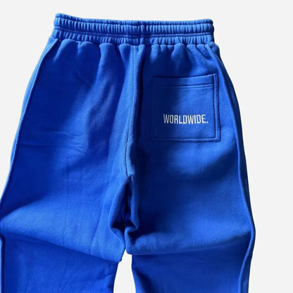 Detailed close-up of the back of the CELESTIC Blue Basic sweatpants. Highlighting the right back pocket with white 'WORLDWIDE' embroidery, the elasticated ribbed waistband, and the premium heavyweight blue cotton fleece fabric.