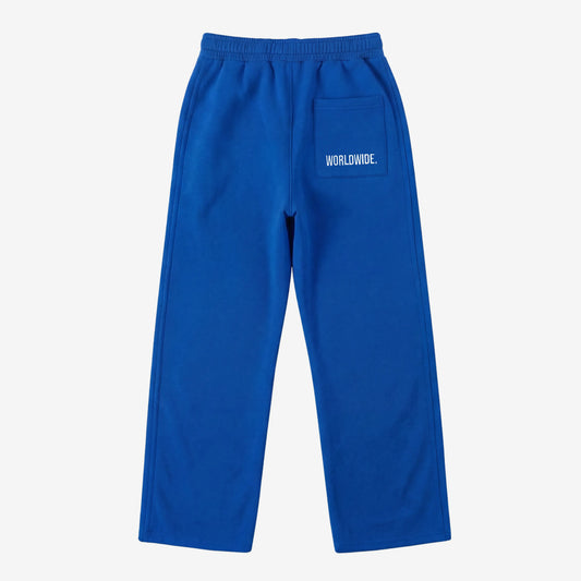 Blue oversized tracksuit sweatpants back view laid flat on a white background. The premium heavyweight cotton fleece CELESTIC Blue Basic pants feature an elasticated ribbed waistband and a right back pocket showcasing the signature white 'WORLDWIDE' embroidery.