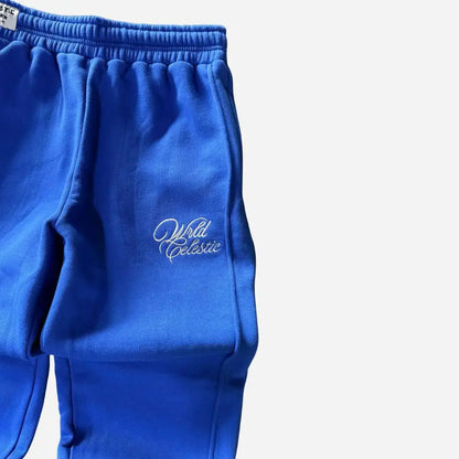 Detailed close-up of the left thigh on the CELESTIC Blue Basic sweatpants. Highlighting the elegant white script logo embroidery, the prominent side panel seam, and the premium heavyweight blue cotton fleece fabric.