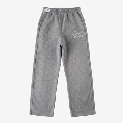 Front view of the CELESTIC Grey Basic sweatpants laid flat on a white background. These premium heavyweight grey cotton fleece pants feature a relaxed straight-leg fit, an elasticated waistband with a white woven brand label, and elegant white script logo embroidery on the left thigh.