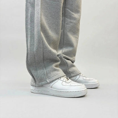Detailed close-up view of the bottom leg on the CELESTIC Grey Basic sweatpants. Highlighting the relaxed straight-leg hem, prominent side panel seams, and the premium heavyweight grey cotton fleece fabric resting on white sneakers.