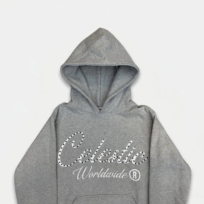 A detailed close-up flat-lay photograph of the upper section of the CELESTIC Grey Gemstone Hoodie on a white background. Highlighting the premium heather grey cotton fleece fabric and the structured double-lined hood. The chest features a large white screen-printed 'Celestic' script logo beautifully embellished with sparkling rhinestones, with the printed text 'Worldwide ®' situated underneath.