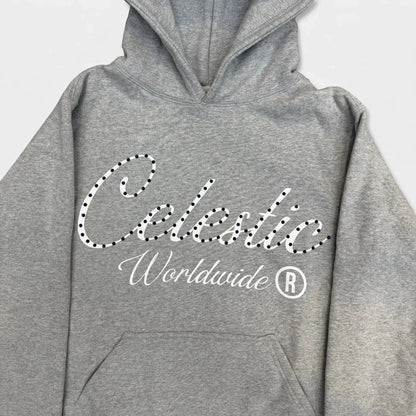 Detailed close-up photograph of the CELESTIC Grey Gemstone Hoodie. The focus is on the chest, showcasing the premium heather grey cotton fleece and the large white screen-printed 'Celestic' script logo, heavily detailed with dark sparkling rhinestones. The white printed text 'Worldwide ®' is clearly visible below the script. The base of the structured hood and the top of the kangaroo pocket frame the logo.