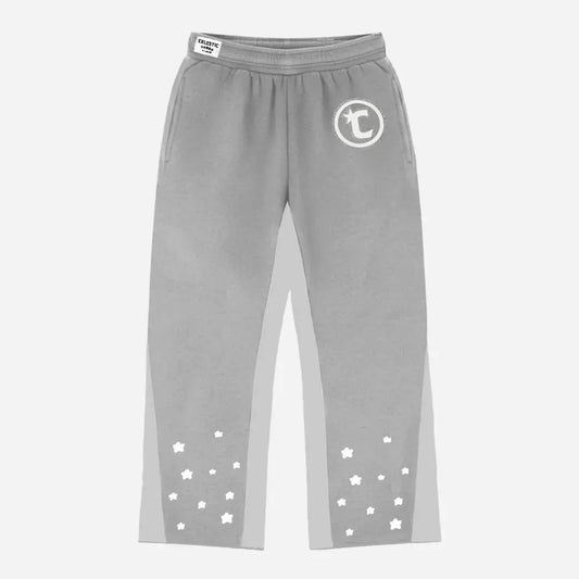 Front view flat-lay photograph of the CELESTIC Grey Star Pants on a white background. These premium heather grey cotton fleece sweatpants feature light grey side panels and a relaxed fit. A white circular 'C' star logo is featured on the left thigh, while the lower legs are detailed with multiple scattered white embroidered stars. A white woven CELESTIC brand label is visible on the elastic waistband.