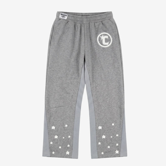 Front view flat-lay photograph of the CELESTIC Grey Star Pants on a white background. These premium heather grey cotton fleece sweatpants feature light grey side panels and a relaxed fit. A white circular 'C' star logo is featured on the left thigh, while the lower legs are detailed with multiple scattered white embroidered stars. A white woven CELESTIC brand label is visible on the elastic waistband.