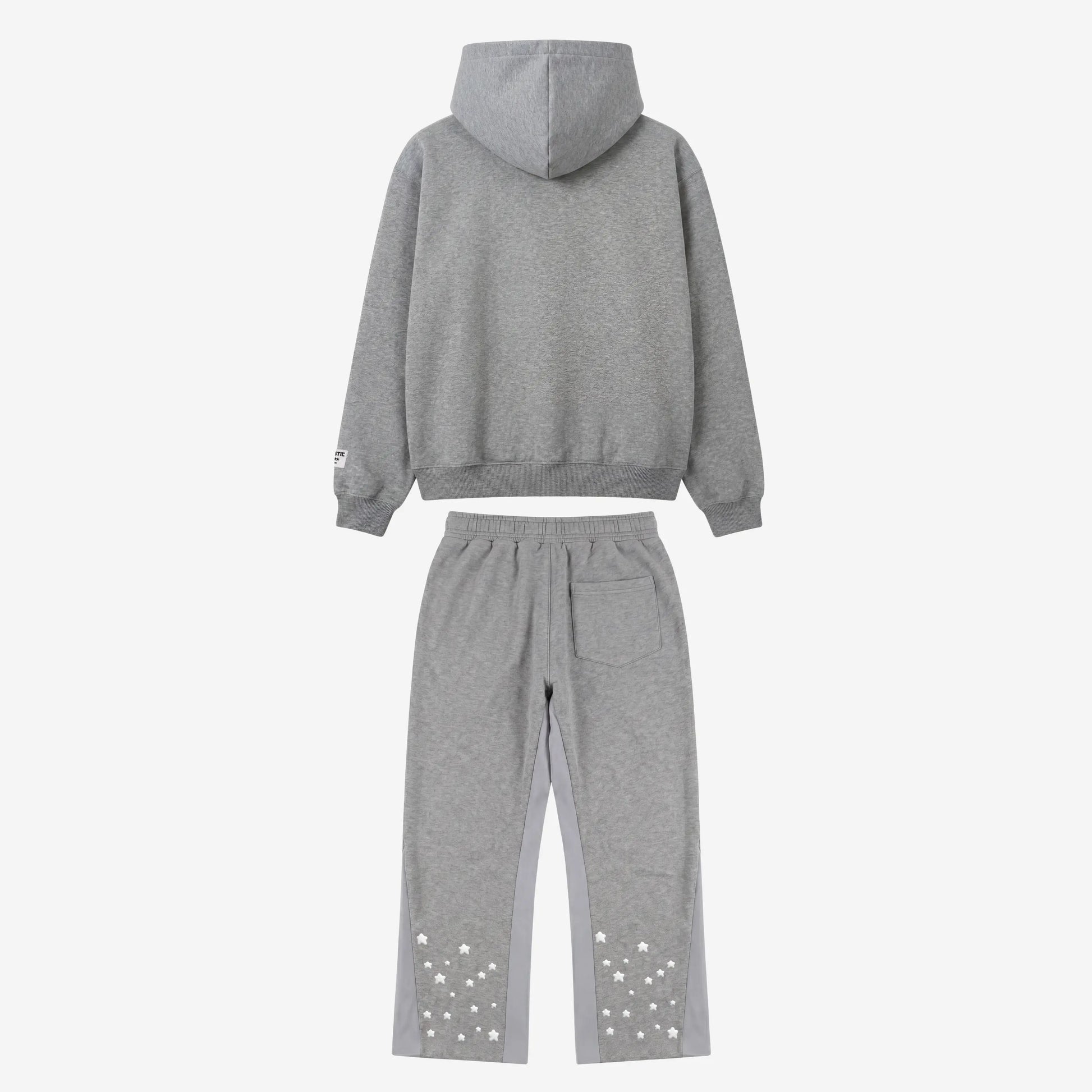 Back view flat-lay photograph of the CELESTIC Grey Star Tracksuit on a white background. The set includes a premium heather grey pullover hoodie with a structured hood and a matching pair of sweatpants. The sweatpants feature light grey side panels and a single back pocket on the right. Both legs are detailed with multiple scattered white embroidered stars on the lower back portion. A woven brand patch is visible on the hoodie's left sleeve.