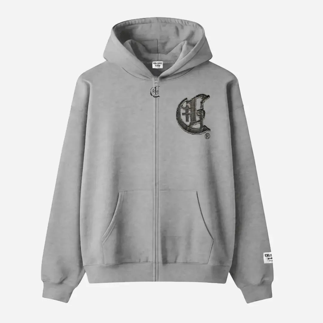 Front view flat-lay photograph of the CELESTIC Grey Zipper Hoodie on a white background. This premium heather grey cotton fleece zip-up hoodie features a silver-tone metal zipper, a spacious kangaroo pocket, and ribbed cuffs and hem. A large, distinctive black gothic-style 'C' star logo is embroidered on the left chest, and a white woven brand patch is visible on the left sleeve cuff.