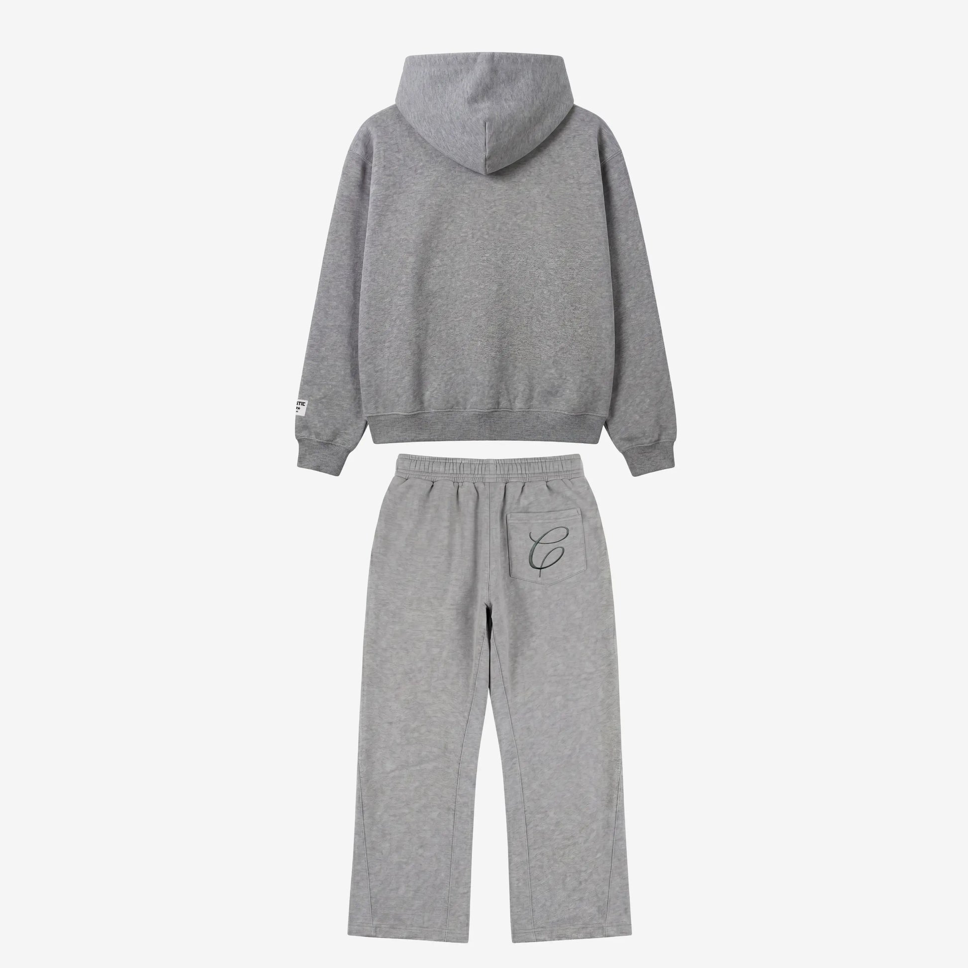 Back view flat-lay photograph of the CELESTIC Grey Zipper Tracksuit on a white background. The set includes a premium heather grey zip-up hoodie with a structured hood and a woven brand patch on the left sleeve cuff. The matching relaxed-fit sweatpants feature a single back pocket on the right side, detailed with an elegant black embroidered 'C' script logo.