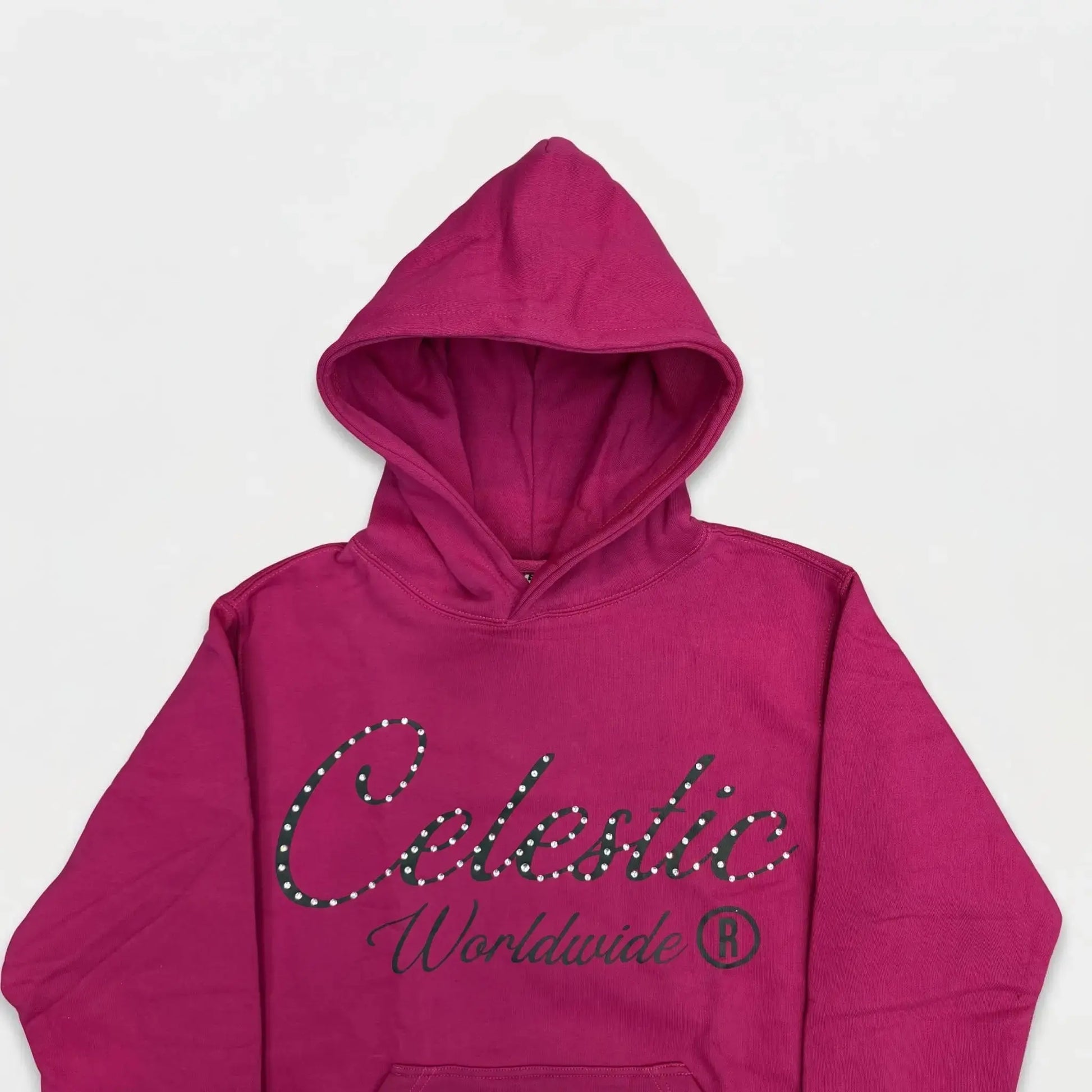 A detailed close-up flat-lay photograph of the upper section of the CELESTIC Pink Gemstone Hoodie. Highlighting the premium vibrant pink cotton fleece fabric and the structured double-lined hood. The chest features a large black screen-printed 'Celestic' script logo beautifully embellished with sparkling rhinestones, with the printed text 'Worldwide ®' situated underneath.