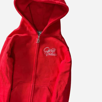 Detailed close-up view of the CELESTIC Red Basic zip-up hoodie. Highlighting the premium heavyweight red cotton fleece fabric, the elegant white script logo embroidery on the chest, the custom metal 'C' zipper pull, and the inner neck brand label.