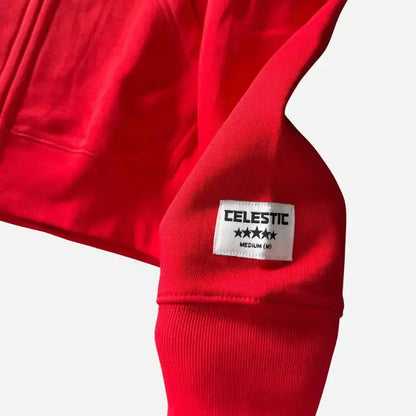 Detailed close-up of the sleeve on the CELESTIC Red Basic zip-up hoodie. Highlighting the premium heavyweight red cotton fleece, the thick ribbed cuff, and the signature white woven CELESTIC brand patch featuring five stars.