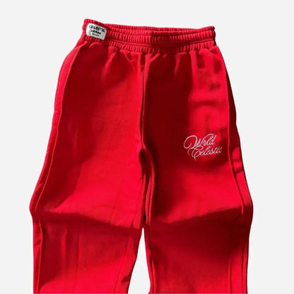Detailed close-up of the upper front of the CELESTIC Red Basic sweatpants. Highlighting the elasticated ribbed waistband with a woven brand tag, prominent side seams, and the elegant white script logo embroidery on the left thigh against the premium heavyweight red fleece.