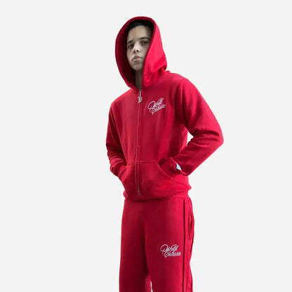 Front view of a model wearing the CELESTIC Red Basic Tracksuit on a white background. The premium heavyweight red fleece set features an oversized zip-up hoodie worn with the hood up, custom metal zipper pull, and matching sweatpants, both highlighting the elegant white script logo embroidery.