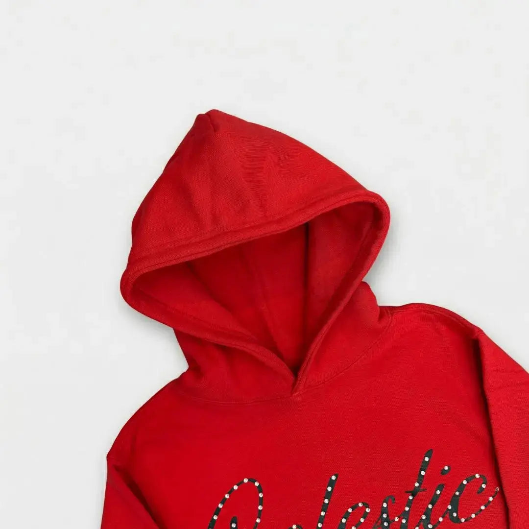 A detailed close-up photograph focusing on the hood of the CELESTIC Red Gemstone Hoodie on a white background. The image highlights the structured double-lined hood and the premium vibrant red cotton fleece fabric. The top portion of the black screen-printed 'Celestic' script logo, beautifully embellished with sparkling rhinestones, is visible on the upper chest.