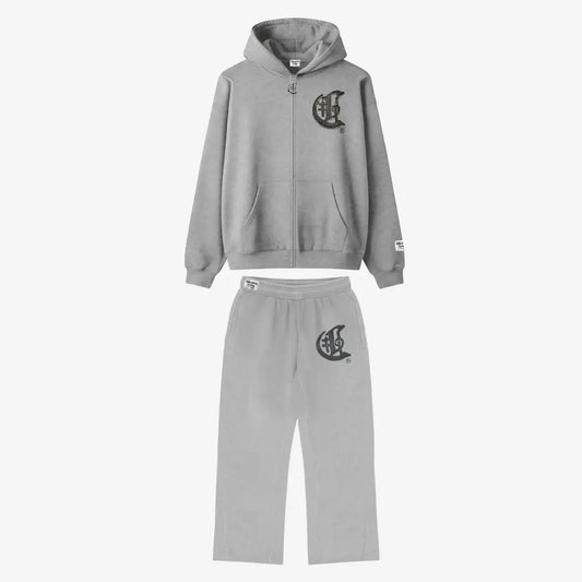 Full front view flat-lay photograph of the CELESTIC Grey Zipper Tracksuit on a white background. The set includes a premium heather grey zip-up hoodie with a kangaroo pocket and a matching pair of relaxed-fit sweatpants. Both pieces feature a large, distinctive black gothic-style 'C' star logo on the left chest and left thigh. The hoodie has a woven brand patch on the left sleeve, and the pants include a matching label on the waistband.