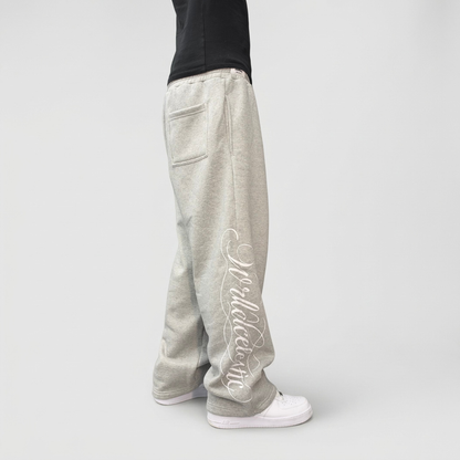 Side view on model of the CELESTIC Grey Script Pants, showing the white Wrldcelestic script print running down the leg.