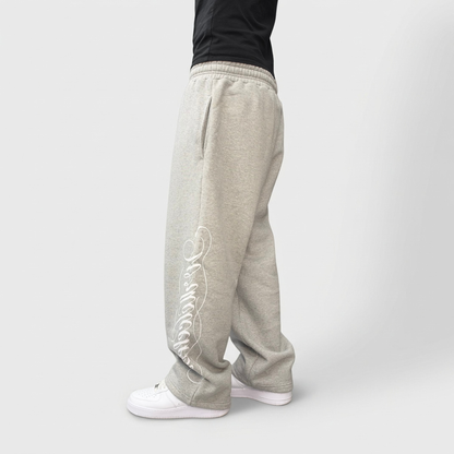 Angled side view on model of the CELESTIC Grey Script Pants in heavyweight heather grey cotton fleece with white script print.