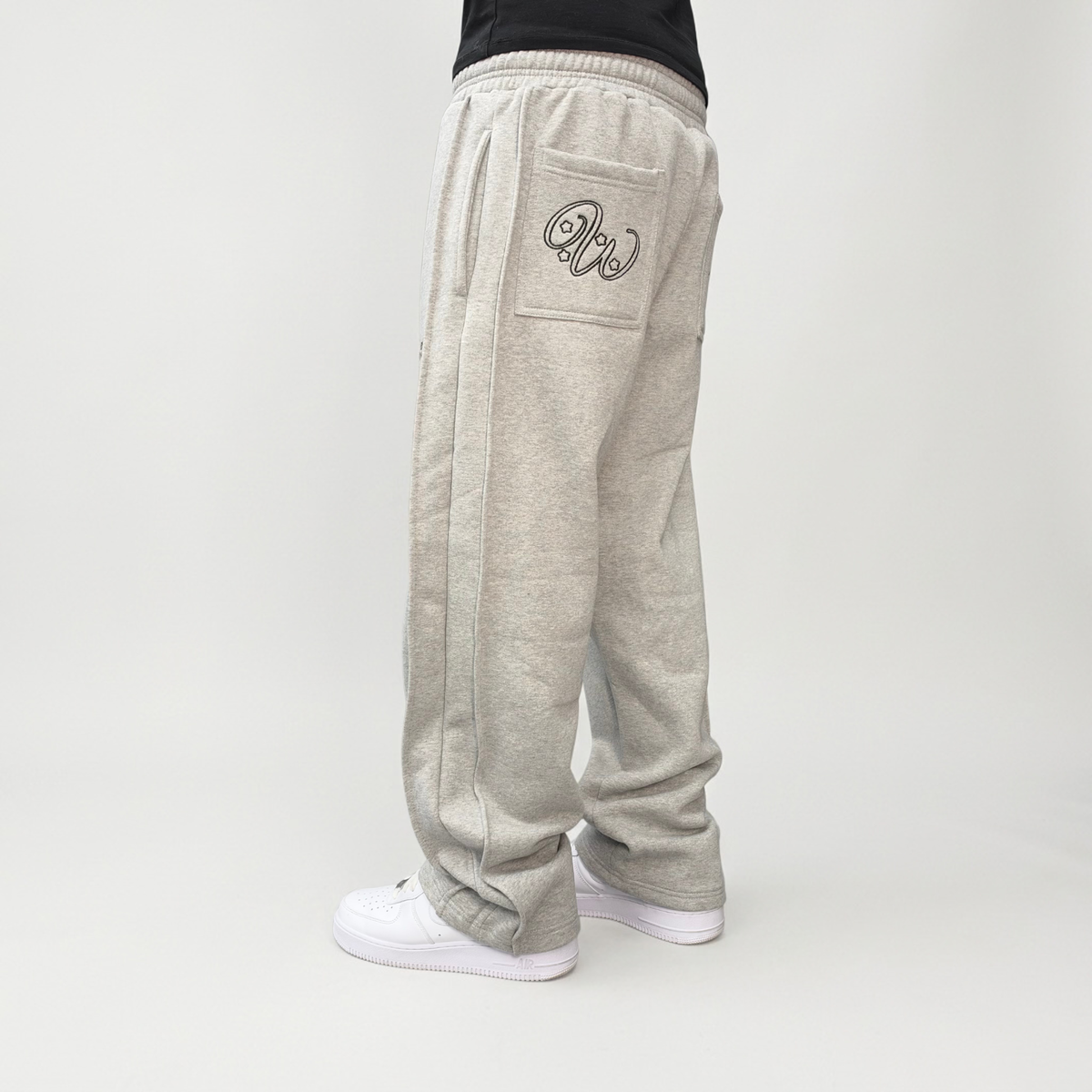 Back view on model of the CELESTIC Grey Outline Pants, showing the outline logo embroidery on the back pocket.