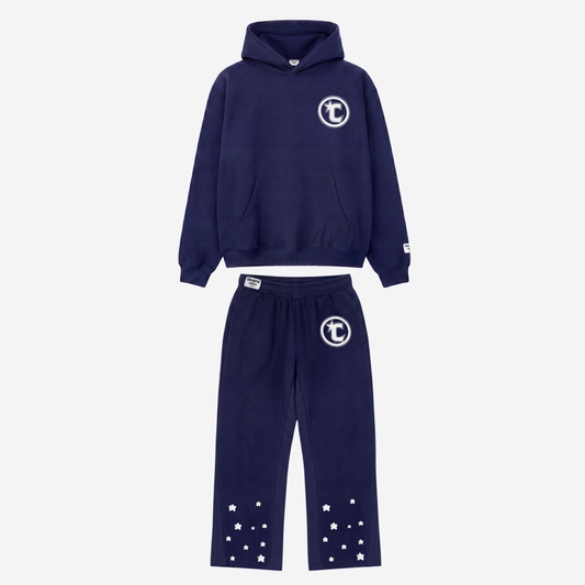 Front view of the CELESTIC Navy Blue Star Tracksuit laid flat on a white background. Heavyweight navy blue cotton fleece pullover hoodie and flared pants with a puff print circular C star logo and rhinestone outline on the chest and thigh, and embroidered stars on the lower legs.