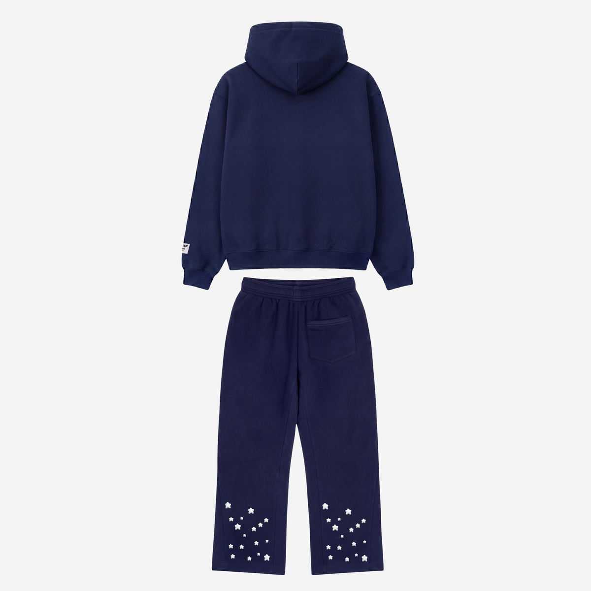 Back view of the CELESTIC Navy Blue Star Tracksuit laid flat on a white background. Heavyweight navy blue cotton fleece pullover hoodie with structured hood and matching flared pants with embroidered stars around the leg openings.